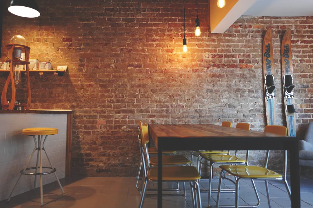 Un café aux murs de brique, tables de bois et ampoules suspendues.